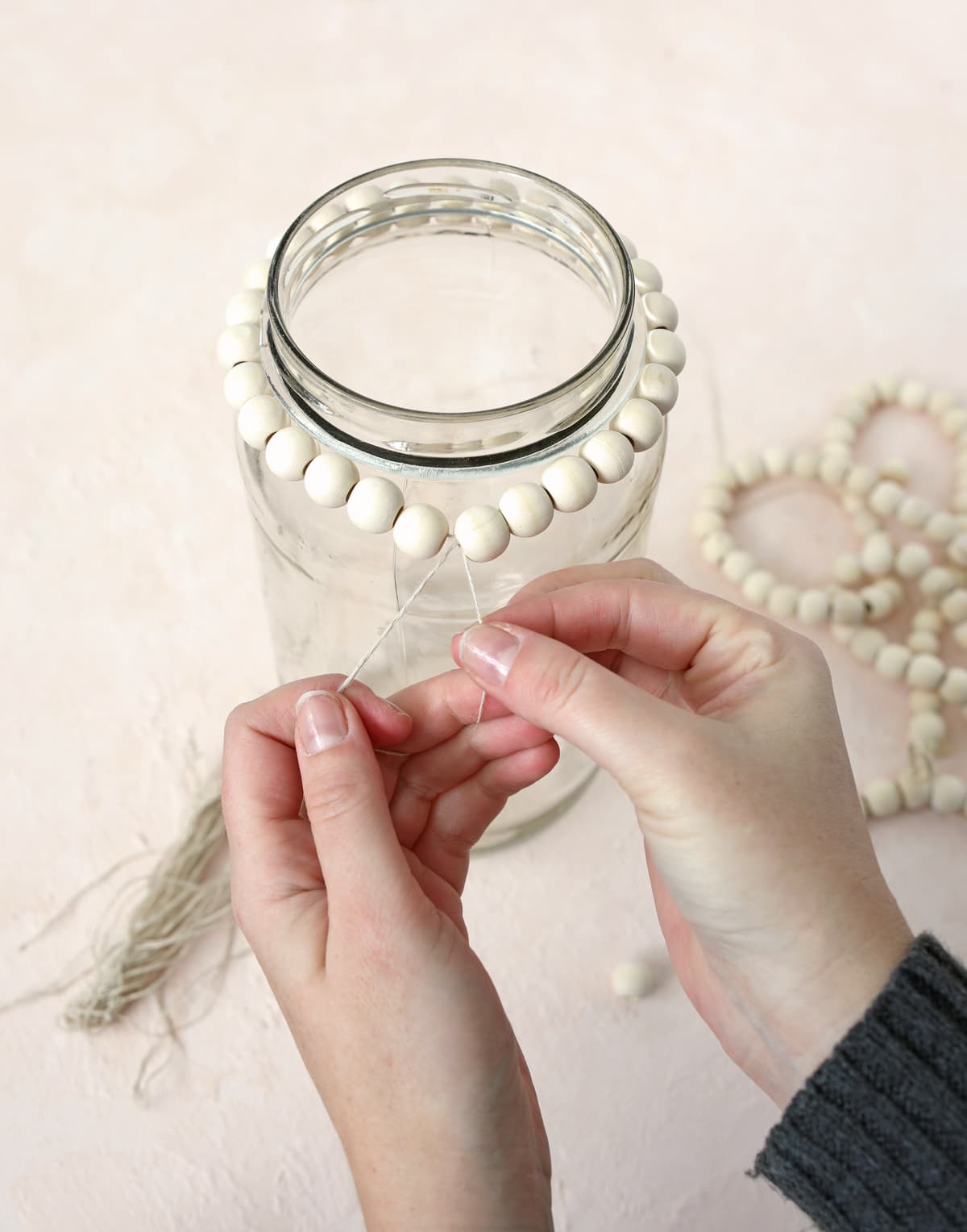 string of wood beads around the top of a glass jar
