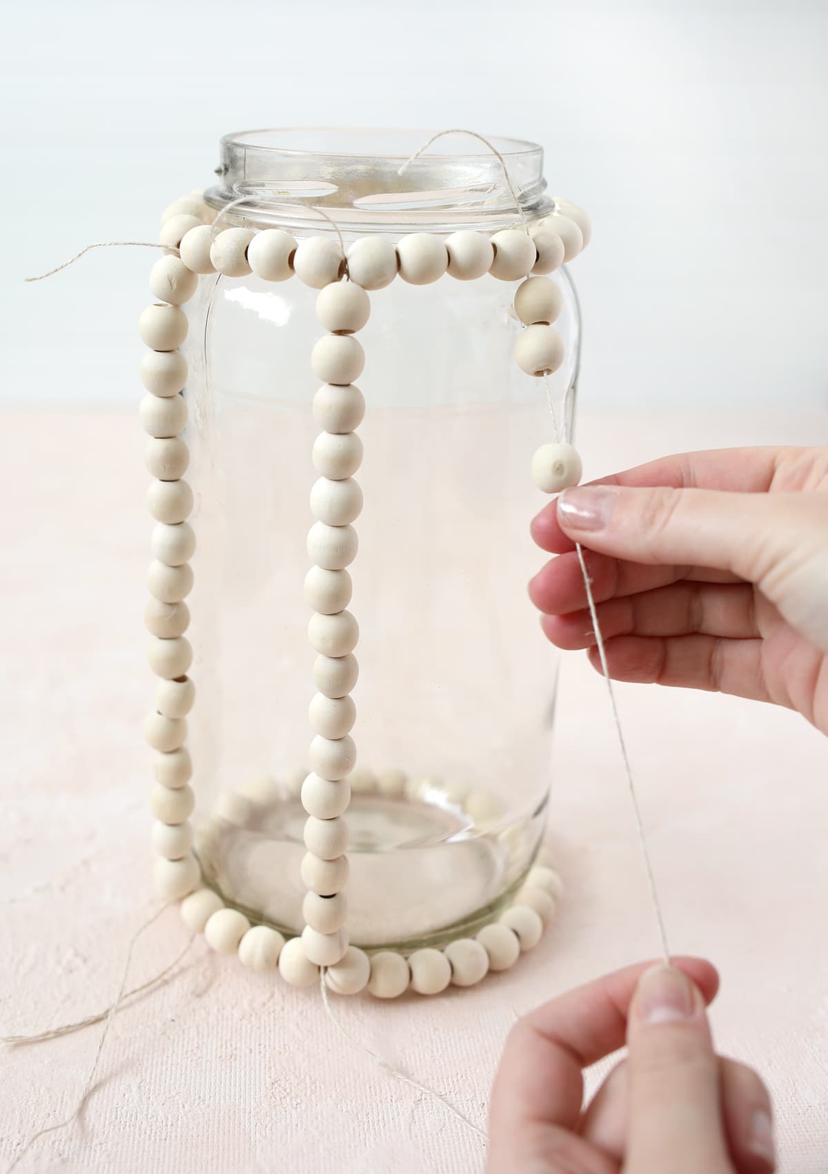 wood beads tied to a glass jar to make a lantern decoration